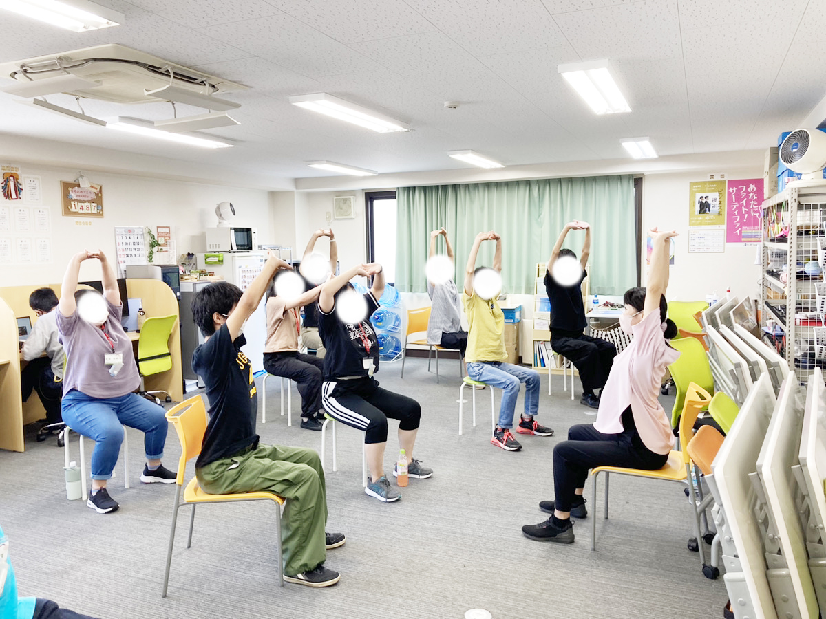 利用者と共に体操を行うスタッフ
